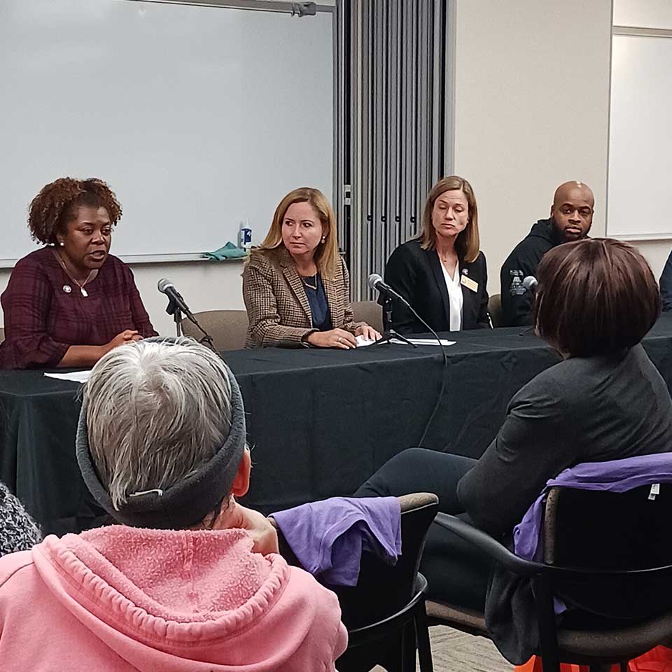 Four panelists sit at a table speaking about the causes of and solutions to gun violence