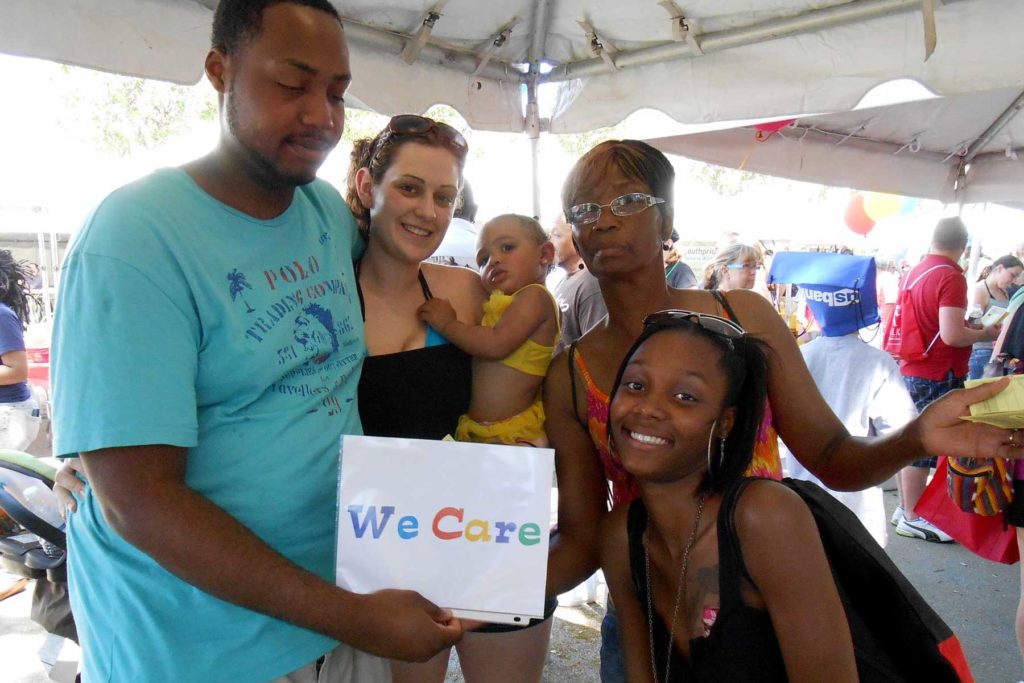 Family smiling at the camera holding a sign that says "We Care"