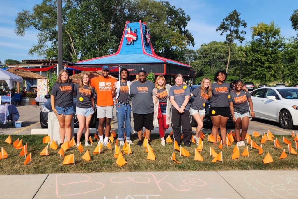 The 2024 WAVE Youth Summer Interns stand with the youth program lead at their Flags for Remembrance Rally