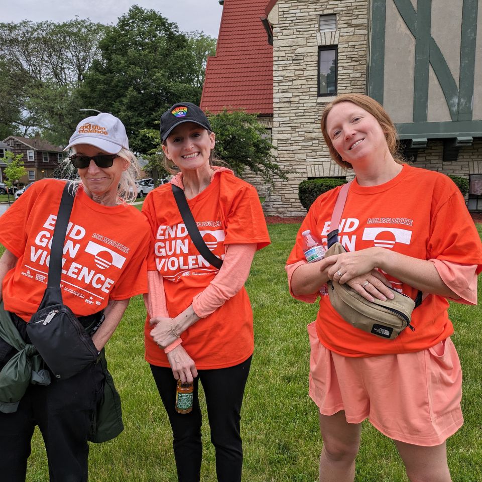 Three people are smiling at the camera. They wear shirts that say End Gun Violence. They seem happy to be at a gun violence prevention event. 