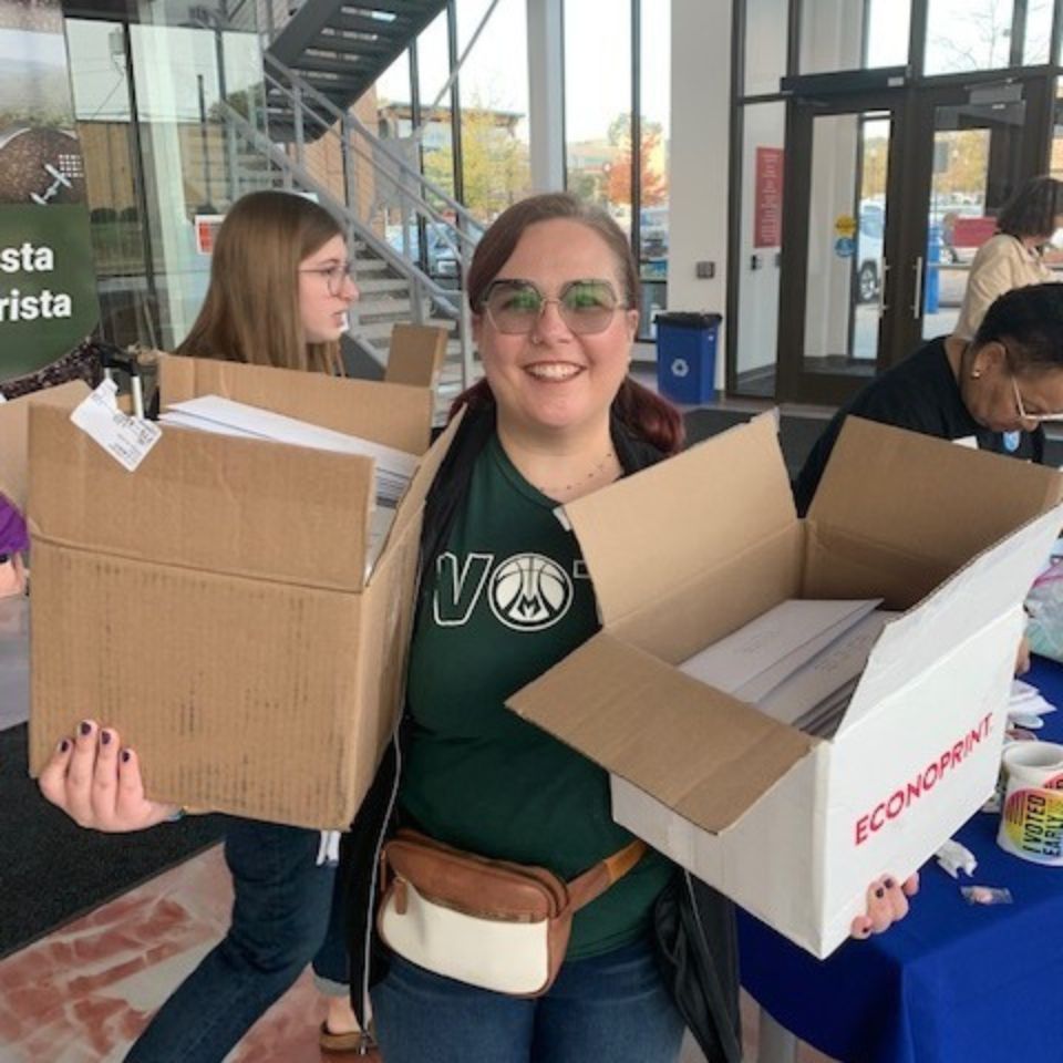 A woman holds two boxes of letters during the Vote No Day of Action. The letters are ready to be mailed.