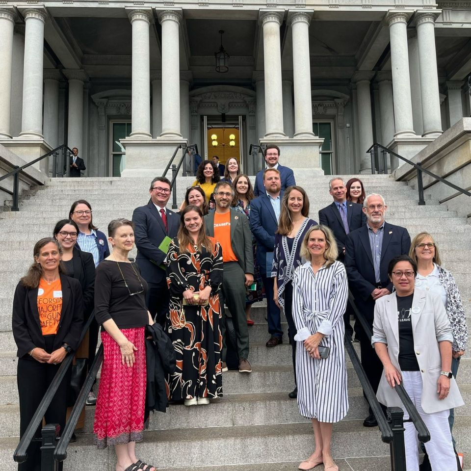 A collection of people stands on the steps of the Capitol Building in Washington D.C. They are all dressed professionally.